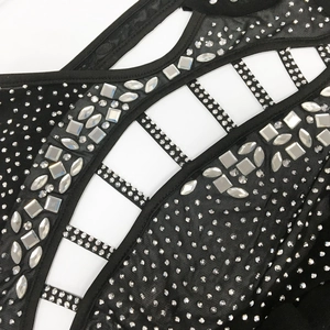 Detail of black mesh fabric with sparkling rhinestones and intricate cut-out patterns