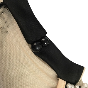 Macro detail of mesh fabric with black spherical buttons and pearl beaded trim accents