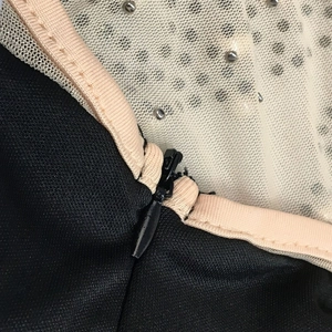 Detail of invisible zipper closure and silver beaded mesh on black satin dress