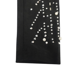 Détail macro du tissu en maille noire avec strass scintillants et perles blanches nacrées