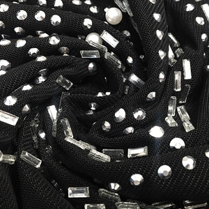 Détail des ornements complexes en strass et perles sur un tissu en mesh noir transparent