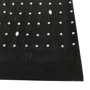 Detail of black mesh fabric with sparkling rhinestones and neat double-stitched hem