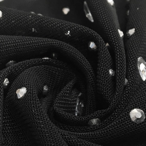 Macro shot of black mesh fabric adorned with sparkling rhinestones and crystal beads