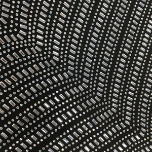 Dettaglio macro di strass su tessuto nero con cristalli argentati rotondi e rettangolari