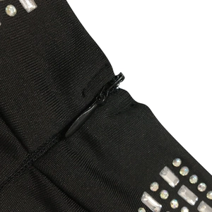Dettaglio del vestito aderente nero con cerniera invisibile e decorazioni in strass
