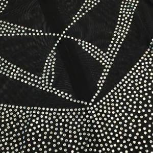 Macro detail of sheer mesh fabric featuring silver rhinestone geometric pattern and sparkles
