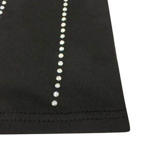 Macro detail of multicolored rhinestones and stitching on a black dress hem