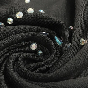 Detailed view of black knitted dress fabric featuring iridescent rhinestones and gems