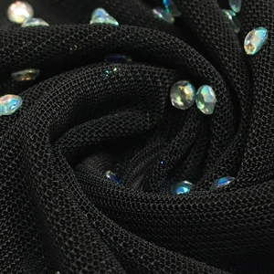 Detailed close-up of black mesh fabric with sparkling iridescent rhinestones