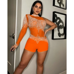 Détail d'une combinaison orange asymétrique ornée de perles et de strass brillants