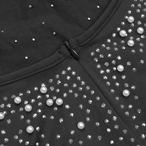 Macro shot of black evening dress featuring elegant white pearls and rhinestone details