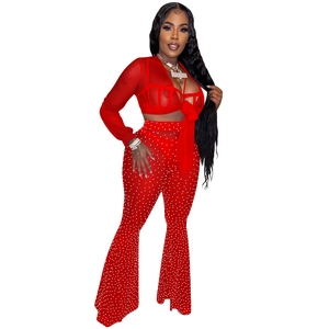 Detail of red mesh three-piece set featuring sheer long sleeves and rhinestone flared trousers