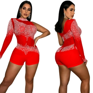 Détail d'une combinaison rouge à une épaule avec manche en mesh et strass brillants