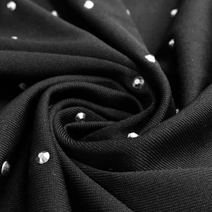 Macro shot of sparkling rhinestones on black stretch fabric for nightclub dress
