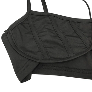 Primer plano del top de punto negro con tirantes finos y costuras decorativas visibles