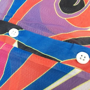 Detailed macro view of sheer mesh fabric with vibrant abstract print and white buttons