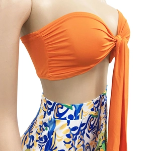Detail view of the orange bandeau top with front tie knot and printed floral maxi skirt