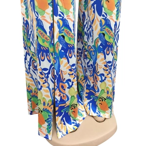 Detail view of tropical print wide leg pants featuring high side slits and vibrant colors