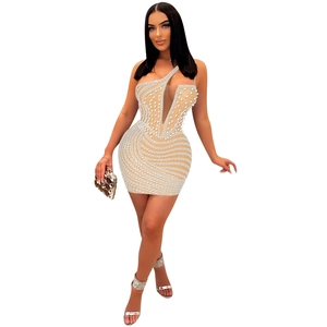 Dettaglio di perle bianche e strass fatti a mano sul tessuto beige del vestito in rete