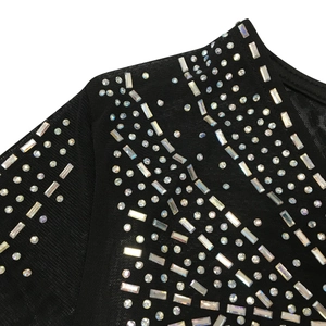 Macro detail of sheer black mesh fabric adorned with silver and iridescent rhinestones