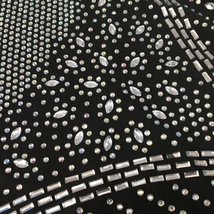 Close-up detail of rhinestone pattern on black mesh dress with glittering crystal deco