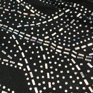 Detailed view of colorful rhinestones on sheer black mesh fabric long sleeve jumpsuit