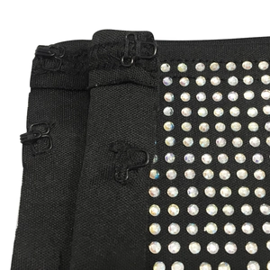 Close-up of black bodycon fabric with hook-and-eye closure and shiny rhinestone details