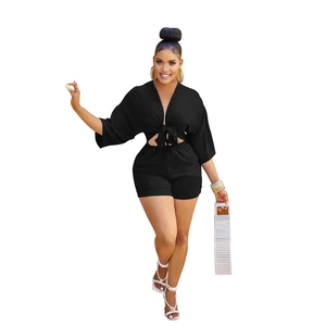 Detail of black two-piece set featuring a deep V-neck tie-up crop top and high-waisted shorts