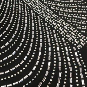 Macro detail of sparkling rhinestones in geometric patterns on black fabric dress