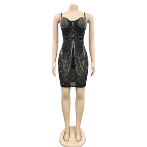 Detail of black mini dress featuring intricate white rhinestone patterns and tassel accents