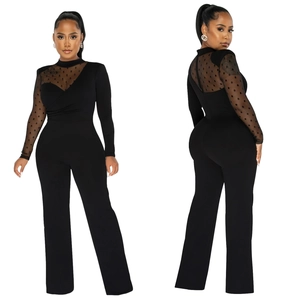 Detail of black mesh jumpsuit featuring sheer polka dot sleeves and pleated cross bodice