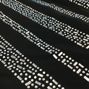 Macro shot of shimmering iridescent rhinestones on black mesh fabric for sexy evening dress