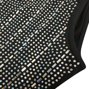 Macro detail of black mesh dress featuring shimmering rhinestones and intricate hot-fix pattern