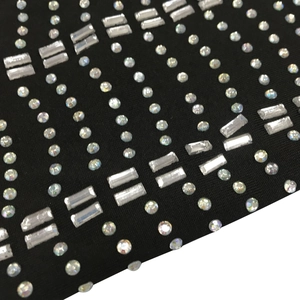 Detail shot of sparkling rhinestones arranged in a geometric pattern on black mesh fabric
