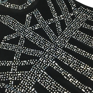 Close-up of sparkling silver rhinestones in starburst pattern on black mesh party dress