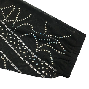 Détail du tissu en maille noire avec strass scintillants et broderie à motifs de cristaux