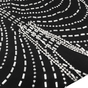 Detailed view of black mesh fabric with intricate silver rhinestone patterns and fringe