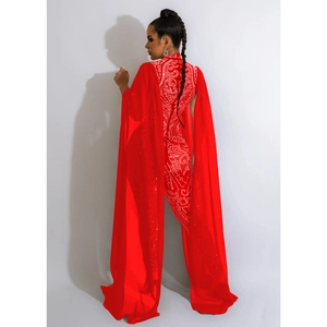 Detail of red sleeveless jumpsuit featuring rhinestone patterns and long chiffon cape