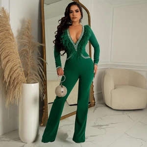 Detail of emerald green jumpsuit featuring deep V-neck with feathers and rhinestone trim