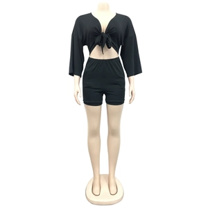 Detail of black two-piece set featuring a V-neck tie-front crop top and high-waist shorts