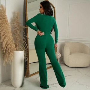 Detail of emerald green jumpsuit featuring luxury feather shoulders and rhinestone cuffs