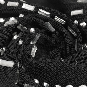 Macro shot of black mesh fabric with sparkling round and rectangular rhinestones