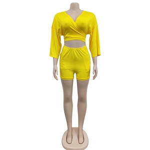 Detail view of bright yellow high waist shorts and matching wrap crop top on mannequin