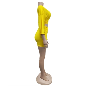Detail view of the yellow short jumpsuit featuring a deep V-neck and stylish waist knot