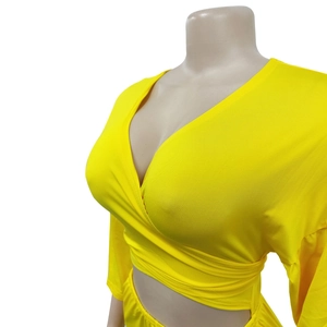 Detail of bright yellow V-neck wrap top showing fine knitted texture and crossover design