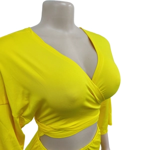Detail of bright yellow wrap crop top with deep V-neck and long sleeves on mannequin