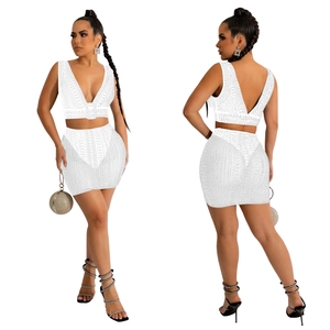 Détail d'un ensemble blanc deux pièces avec haut sans manches décolleté en V et mini-jupe