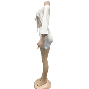 Detail view of white two-piece set featuring a tie-front crop top and bodycon mini skirt