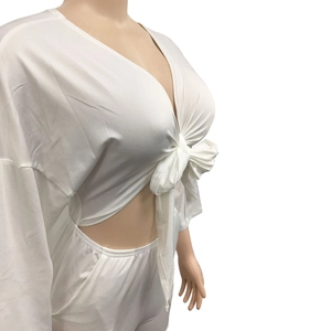 Detail of white two-piece set featuring a V-neck tie-front crop top and matching trousers