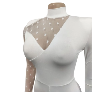 Close-up of white slim fit jumpsuit with sheer polka dot mesh panels and high neck collar
